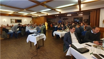 In einem Saal sitzen Männer an Tischen. 
