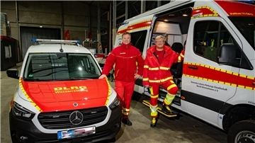 Zwei Männer an Rettungswagen der DLRG.