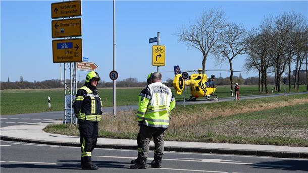 Drei Schwerverletzte bei Unfall auf der B212 in Nordenham: Straße voll gesperrt Einsatzkräfte stehen auf der Straße. Im Hintergrund ist der Rettungshubschrauber zu sehen.