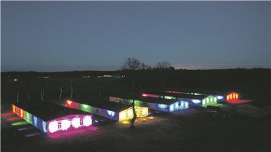 Die erhaltenen Holzbaracken auf dem Gelände der Sandbosteler Gedenkstätte wurden in Regenbogenfarben angestrahlt.
