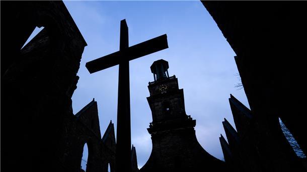 Ein großes Kreuz steht vor einer Kirche.