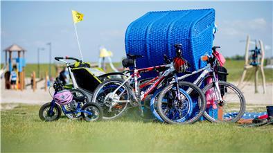 Die Fahrräder einer Familie lehnen am Friesenstrand im Landkreis Wesermarsch an einem blauen Strandkorb.