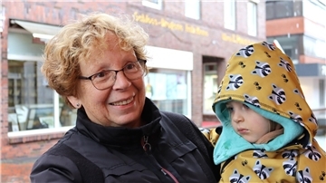 Verregneter Sonntag in Zeven: Regionalmarkt trotzt Wind und Wetter Frau mit Kind auf Arm