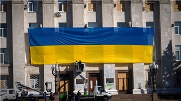 Die Fassade eines Verwaltungsgebäudes in der ukrainischen Stadt Cherson wird mit einer riesigen Nationalfahne geschmückt.
