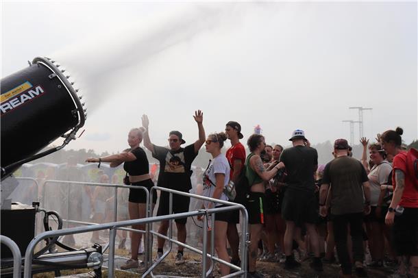 Die Festival-Besucher suchen Abkühlung unter der Fontäne.