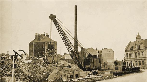 Ein Schwarz-Weiß-Foto aus dem Jahr 1944: Es zeigt einen Kran und einen Schuttberg. Dahinter und auch rechts im Bild stehen einzelne Häuser.