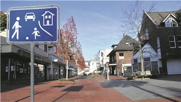 Autos müssen langsam fahren Die Fotomontage zeigt ein Spielstraßenschild in der Fußgängerzone.