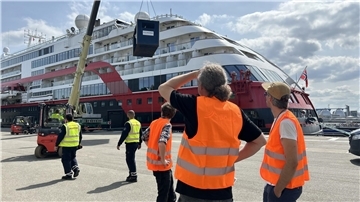 Fridtjof Nansen bei der Übernahme von Meerestechnik in Hamburg. Im Vordergrund sind Männer in Arbeitskleidung mit Sicherheitswesten zu sehen. Im Hintergrund ein großes Schiff. 