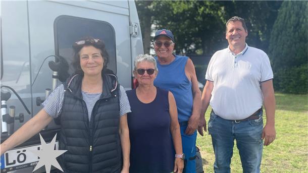 Eine Gruppe steht vor einem Campervan.