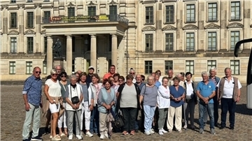 Große Reisegruppe Älterer vor einem Gebäude mit historischer Fassade