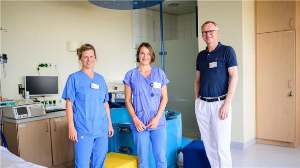 Kreißsaal zum Wohlfühlen: zwei Hebammen bei der Geburt Die Hebammen Franziska Pfeil (l-r) und Antje Kuhrau sowie Peter Dall, Chefarzt, stehen in einem Kreißsaal des Klinikums Lüneburg. Seit diesem Monat können Frauen in Begleitung von zwei Hebammen entbinden.