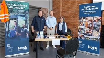 Drei Menschen bei einer Messe an einem Stand
