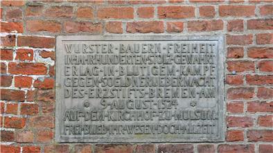 Die Inschrift erinnert an die Schlacht auf dem Mulsumer Kirchhof: „Wurster Bauern Freiheit in Jahrhunderten stolz gewahrt, erlag in blutigem Kampf gegen Söldnerübermacht des Erzstifts Bremen am 9. August 1524 auf dem Kirchhof zu Mulsum. Frei blieb ihr Wesen doch allzeit.“