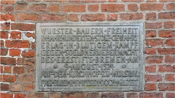 Die Inschrift erinnert an die Schlacht auf dem Mulsumer Kirchhof: „Wurster Bauern Freiheit in Jahrhunderten stolz gewahrt, erlag in blutigem Kampf gegen Söldnerübermacht des Erzstifts Bremen am 9. August 1524 auf dem Kirchhof zu Mulsum. Frei blieb ihr Wesen doch allzeit.“