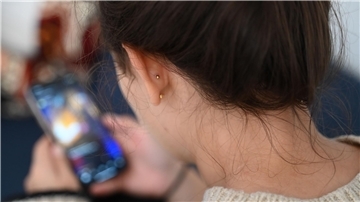 Eine junge Frau schaut auf ihr Handy.