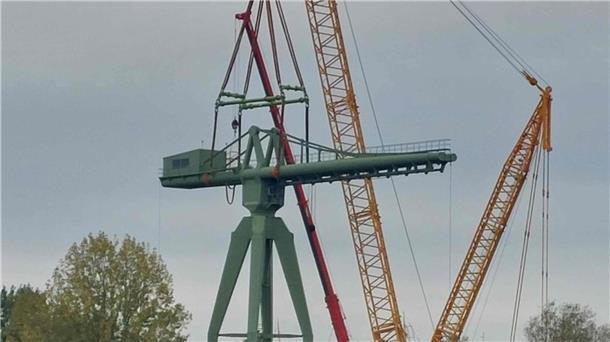 Ein gelber Raupen-Kran hebt die Kanzel des historischen grünen Krans auf das Unterteil.  