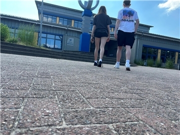 Zwei Jugendliche gehen auf ein Schulgebäude zu.