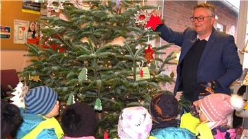Kinder schmücken einen Weihnachtsbaum.