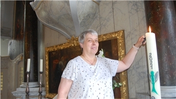 Eine Frau entzündet eine Kerze.