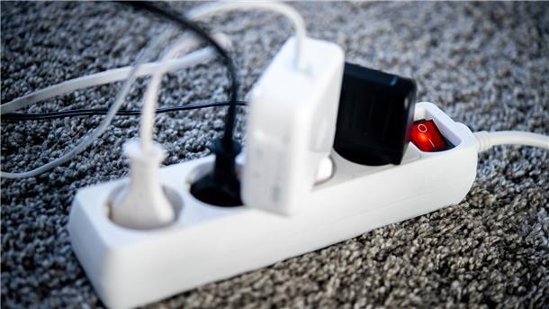 Die Netzstecker verschiedener Geräte sind in einem Wohnzimmer in eine Steckdosenleiste gesteckt. 