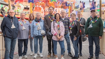 Eine Gruppe Menschen steht vor einem Fahrgeschäft auf dem Jahrmarkt