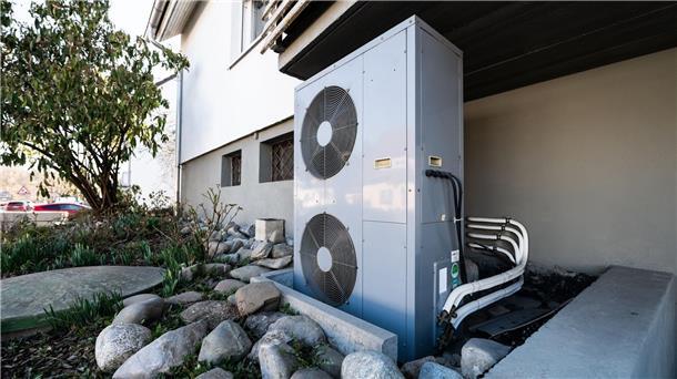 Wärmepläne für alle Kommunen - und früher als gedacht Die Lüftungsanlage einer Wärmepumpe steht vor einem Wohnhaus.