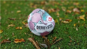 Ein kaputter Fußball mit wenig Luft liegt auf nassem Rasen.