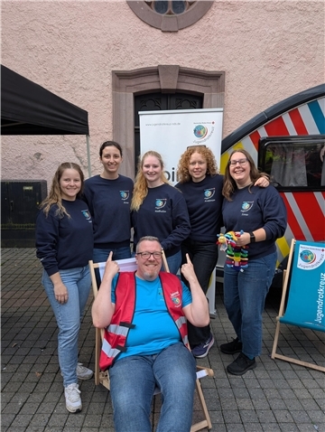 5 junge Frauen in dunkelblauen Sweatshirts und ein Mann lächeln