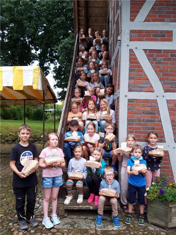 Kinder mit selbst gebackenem Brot an einem Heimathaus