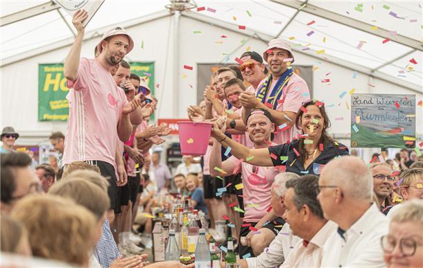 Eine Gruppe Männer, die auf Bänken stehen und rosa Trikots tragen. 