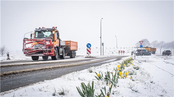 Ein Streufahrzeug fährt über eine Straße.