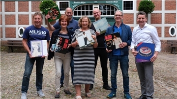 Die Mitglieder des Teams Netzwerk Plattenspende halten verschiedene Schallplatten in die Höhe.