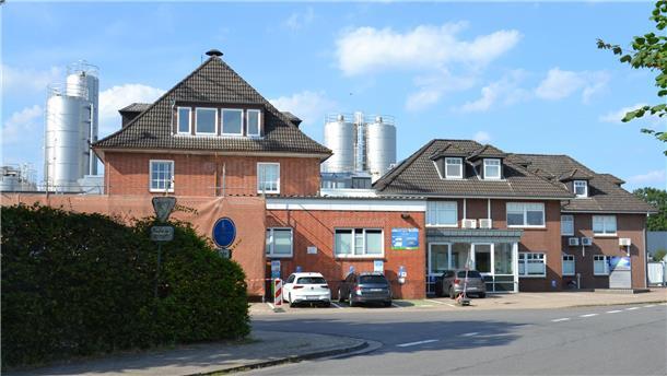 Molkerei Elsdorf: Vom privat gegründeten Betrieb zum internationalen Unternehmen Mehrere rot geklinkerte Gebäude stehen an einer Straße.