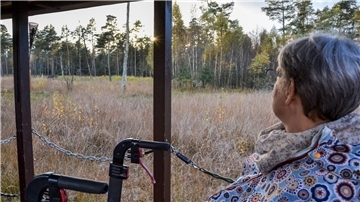 Eine Frau sitzt im Waggon, vor ihr steht ihr Rollator.