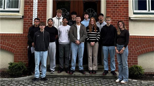 Auszubildende in verschiedenen Berufen stehen für ein Gruppenfoto vor einem Haus.
