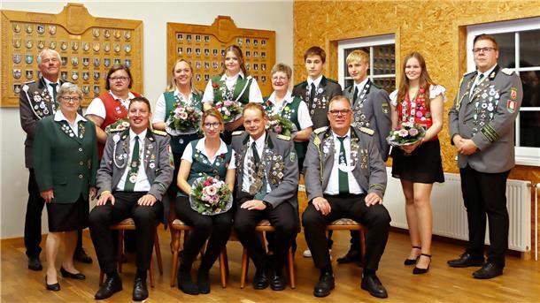 Männer und Frauen in Schützenuniform posieren für ein Foto. 