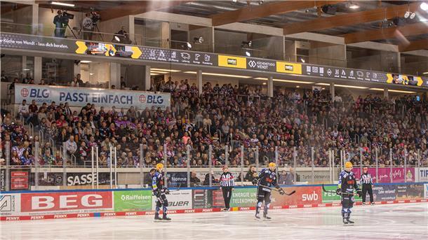 Drei Eishockey-Spieler stehen auf dem Eis. Oberhalb der Eisfläche sind neue Logen in der Eisarena Bremerhaven zu sehen.