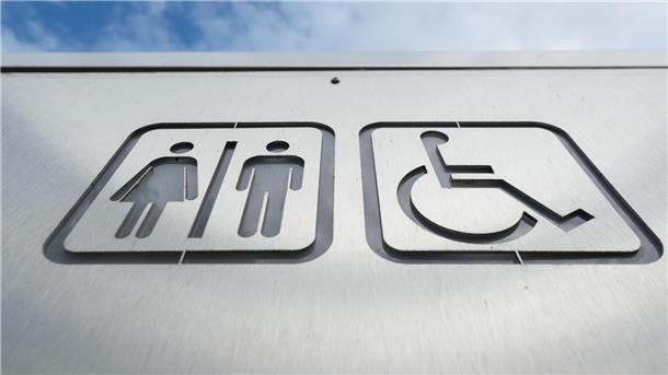 Ein Schild weist in der Innenstadt den Weg zu einer öffentlichen Toilette. 