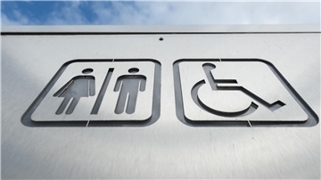 Ein Schild weist in der Innenstadt den Weg zu einer öffentlichen Toilette. 