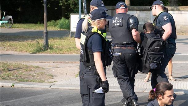 Klimaaktivisten stören bundesweit den Verkehr Die Polizei trägt einen Aktivisten der Gruppe Letzte Generation weg, der mit anderen die Fahrbahnen rund um die Siegessäule in Berlin blockiert hat.