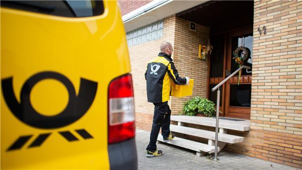 Ein Zusteller bringt Post an eine Haustür