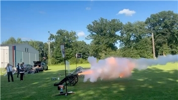 Eine Kanone feuert auf offenem Feld Schüsse ab.