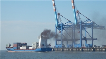 Schiff mit Abgaswolke vor dem Containerterminal