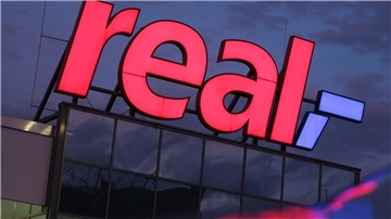 Das Logo "real" an einer Fassade.
