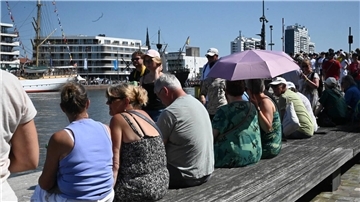 Menschen auf einer Bank am Wasser.