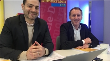Zwei Politiker sitzen vor einem FDP-Plakat 