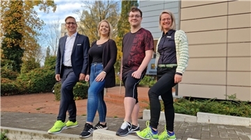 Zwei Männer und zwei Frauen stehen nebeneinander und präsentieren ihre Laufschuhe. 