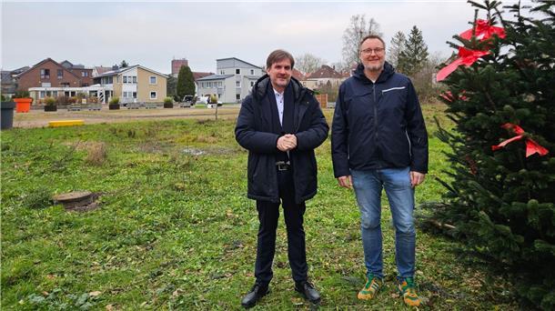 Zwei Männer stehen auf einer Brachfläche.