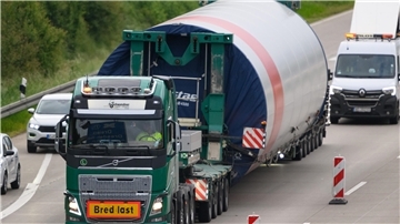 Ein Lkw, der ein Teil einer Windkraftanlage über eine Straße transportiert.