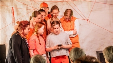 Acht Kinder stehen auf der Bühne und spielen Theater. 